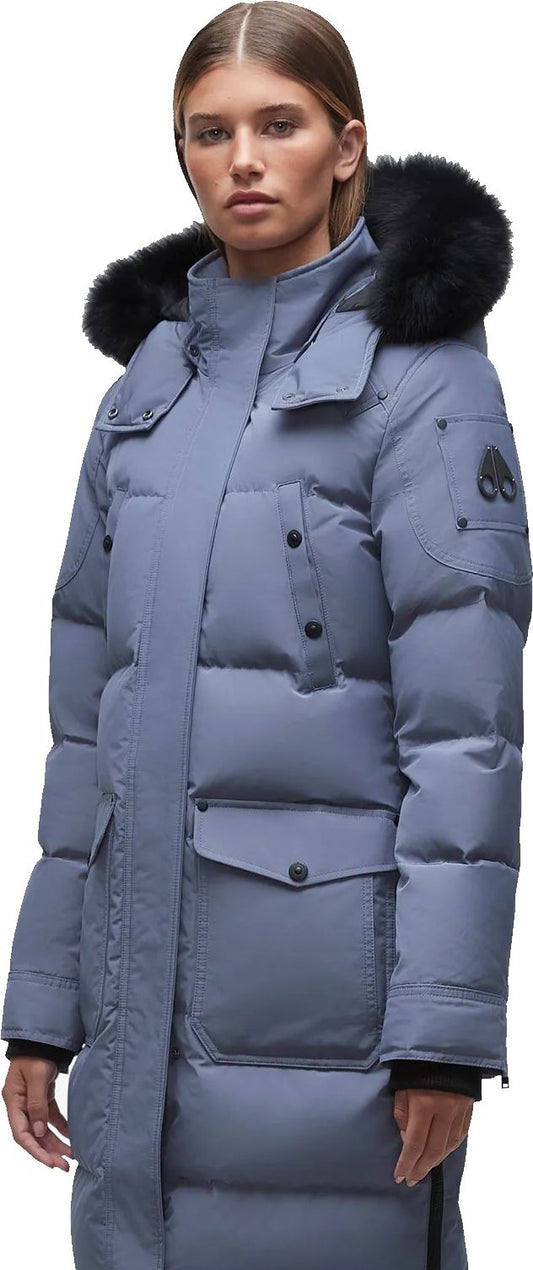 A woman wearing a long blue puffer coat with black fur trim around the hood.