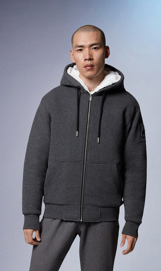 A man wearing a heather grey zip-up hoodie with white sherpa lining, front pockets, and matching sweatpants.