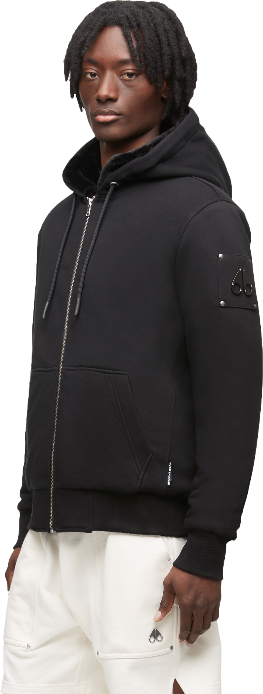 A person wearing a black zip-up hooded sweatshirt and white shorts.