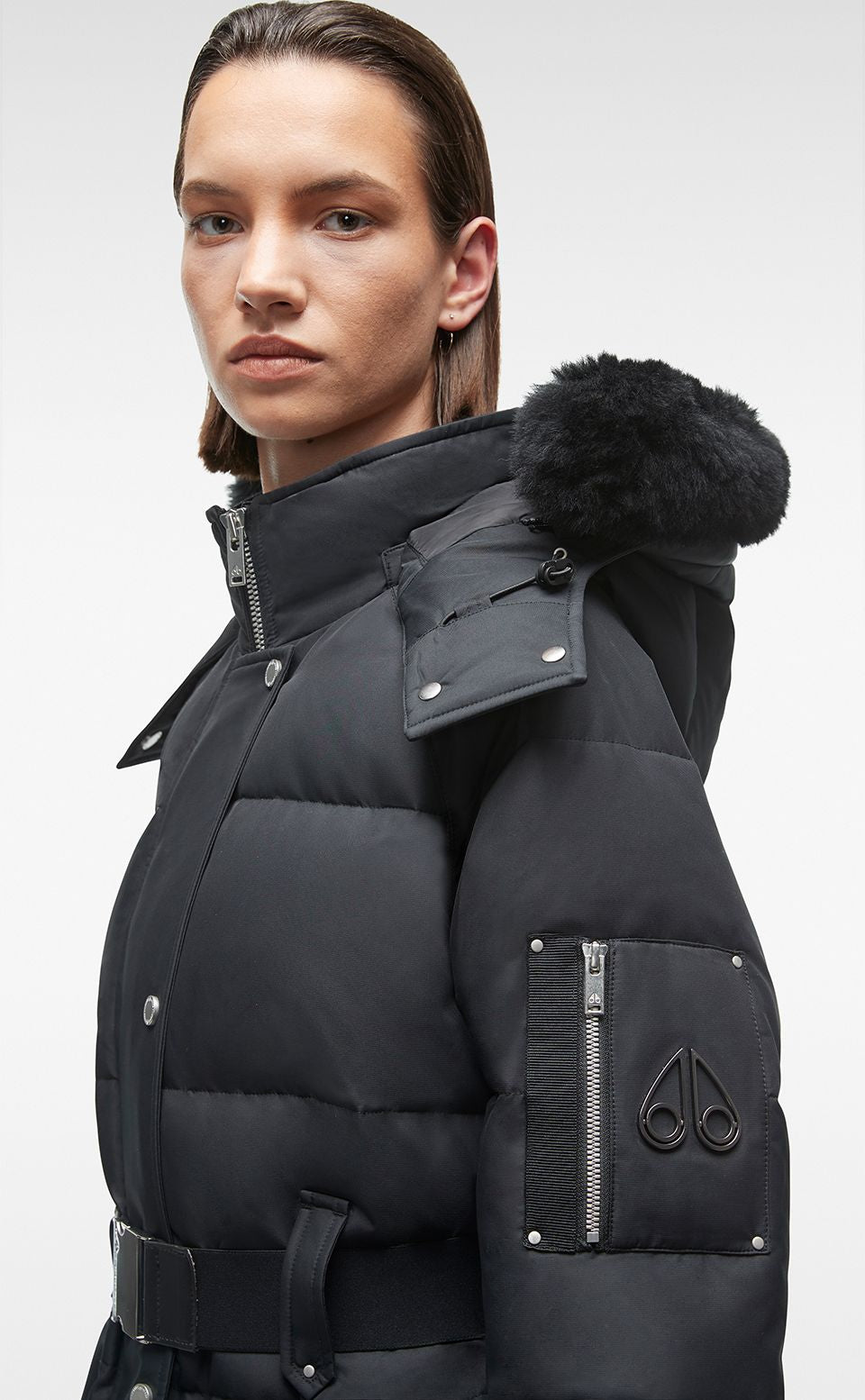 A black, belted, puffy winter coat with a fur-trimmed hood and moose logo.