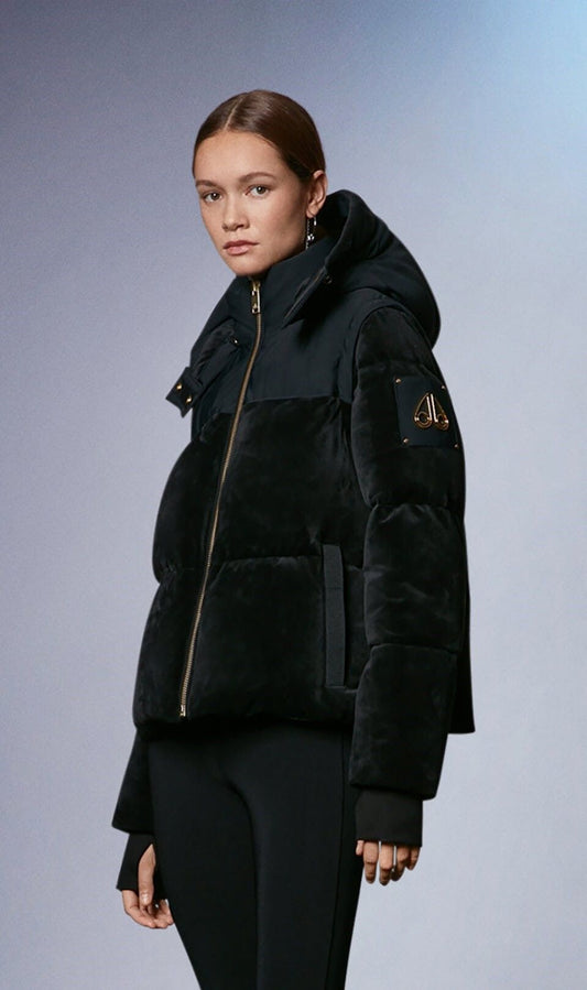 A woman wearing a short, black, hooded puffer coat with a fuzzy texture.