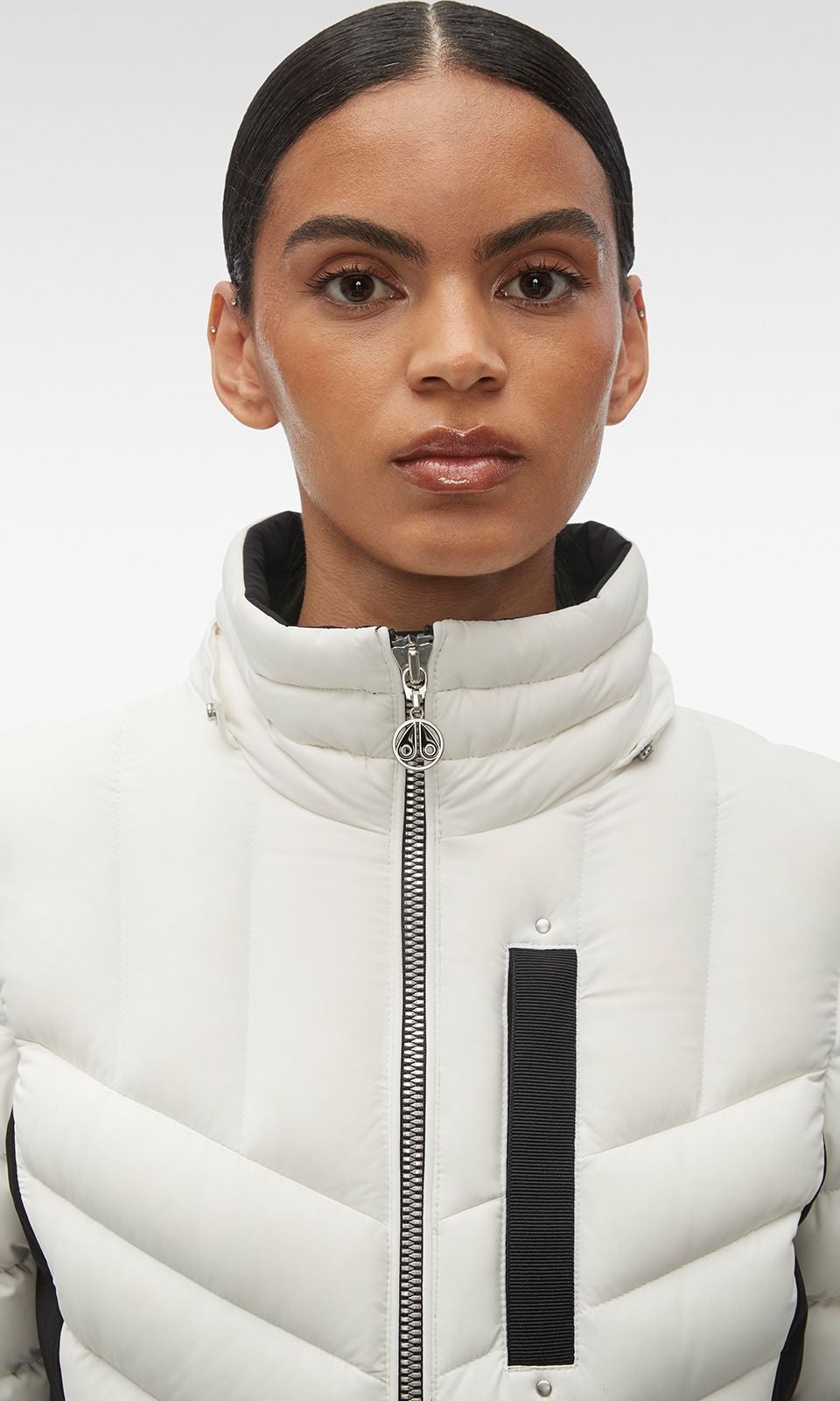 Woman in white quilted puffer jacket with black stripe.