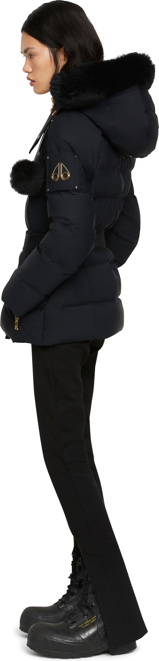 A person in a black winter jacket with fur trim, black pants and black boots.