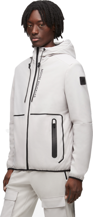 A person wearing a light gray hooded jacket with black zippers and detailing.