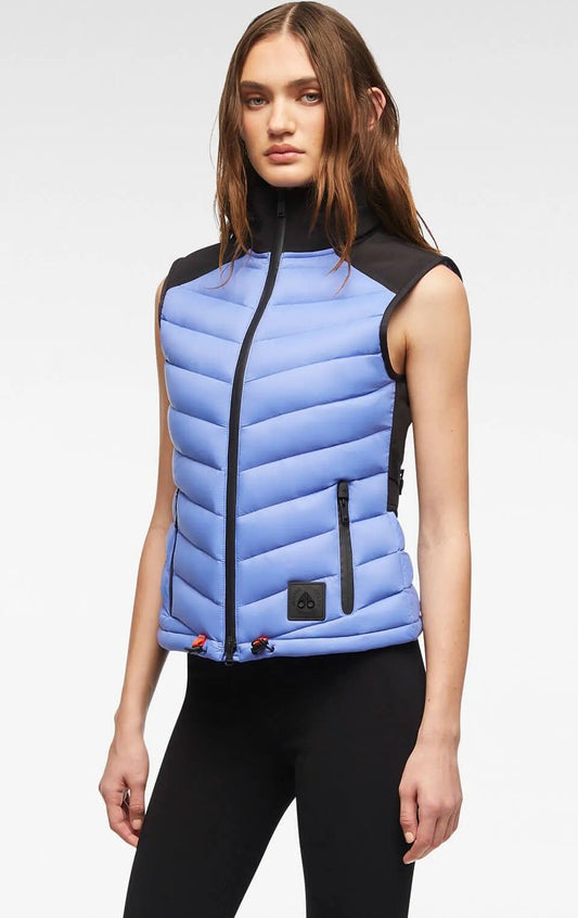 A woman wears a light blue puffer vest with black shoulders and collar.
