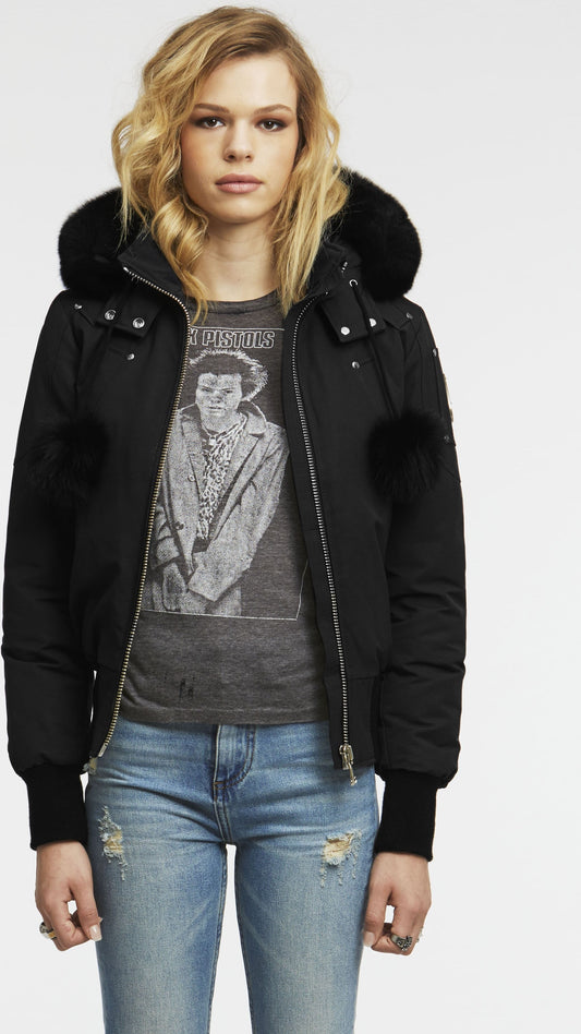 A person wearing a black winter jacket with a fur-lined hood and distressed blue jeans.