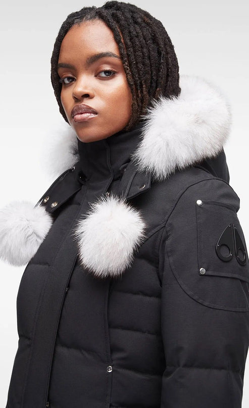 Black parka with white fur trim and pom-poms, close-up.