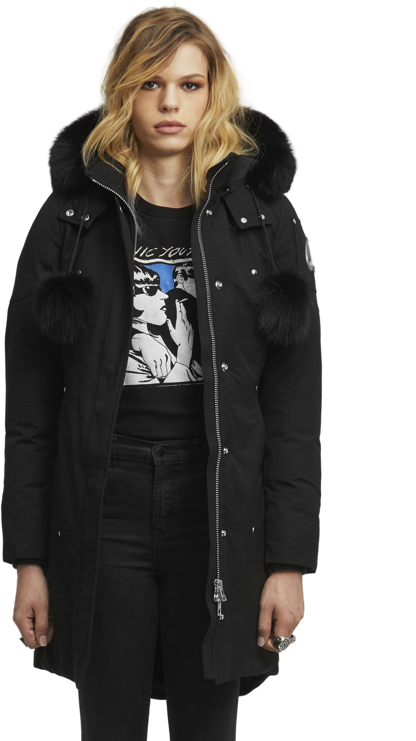 A woman in a black winter coat with fur trim on the hood and fur pom-poms.