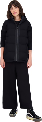 A woman wearing a black vest with a zipper and black pants.