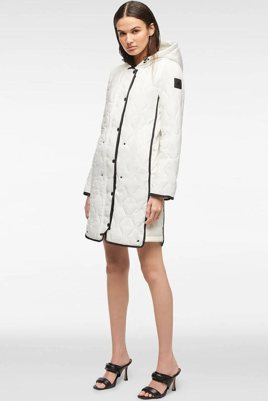 Woman wearing a white quilted jacket with black trim and black heeled sandals.