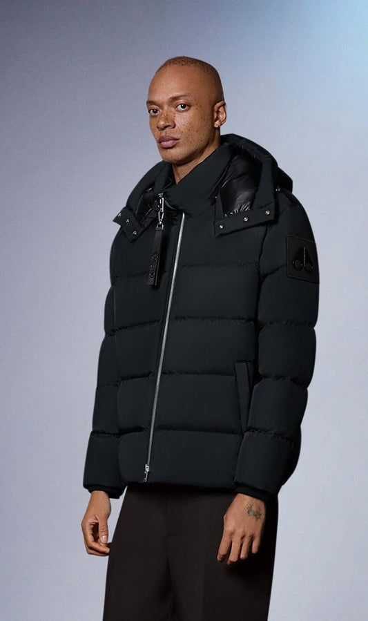 A person wearing a black puffer jacket with a zipper, hood and attached lanyard.