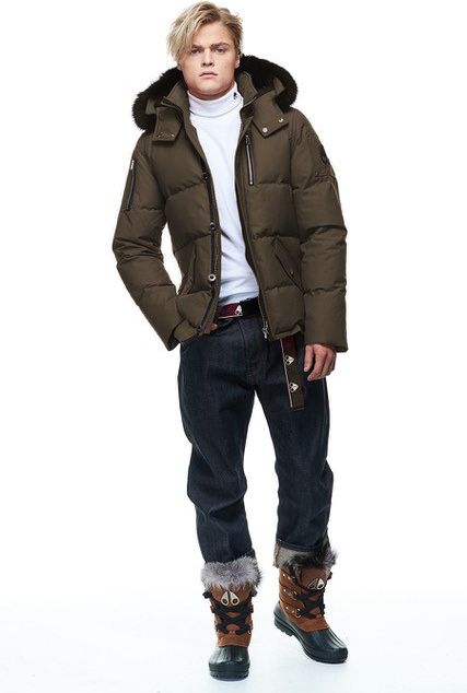 A person wearing a down jacket with a fur-lined hood, white turtleneck, dark denim jeans, a belt and a pair of fur-trimmed boots.