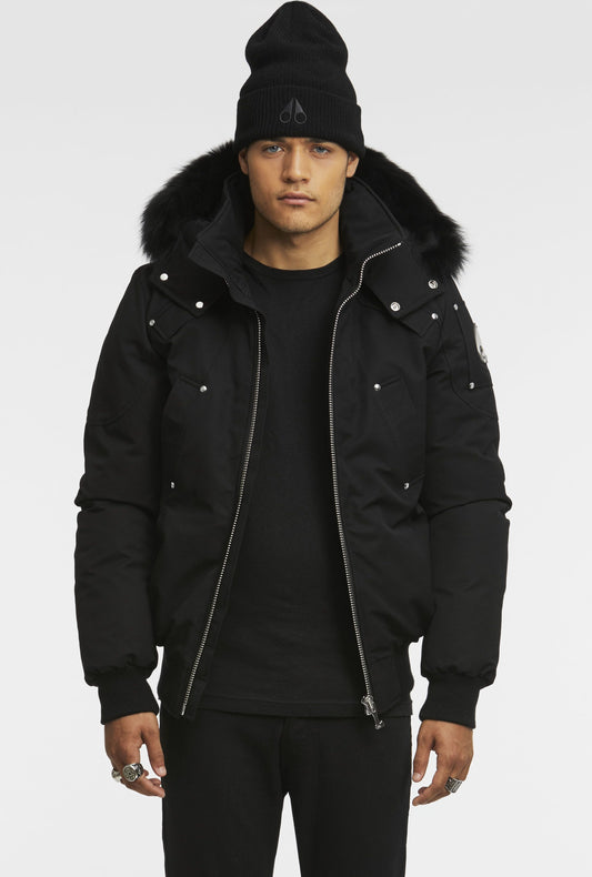 Man in a black winter jacket with a fur-lined hood and a black beanie.
