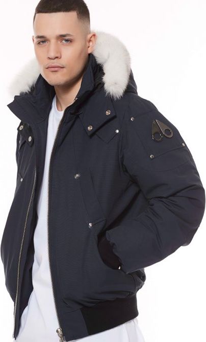 A man wearing a navy blue, hooded winter jacket with white fur trim.