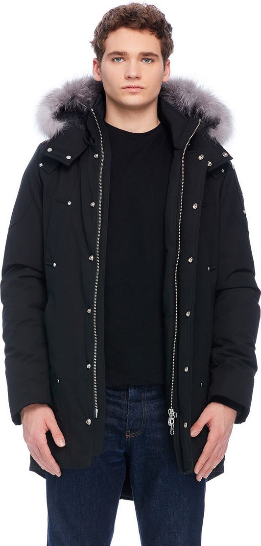 A person wearing a black winter coat with fur trim.