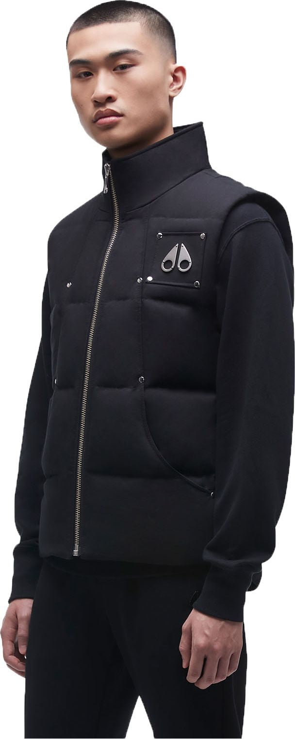 A person in a black vest with a high collar and a silver zipper.