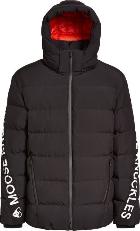 A black hooded puffer jacket with white text “MOOSE KNUCKLES” down the left sleeve and orange hood interior.