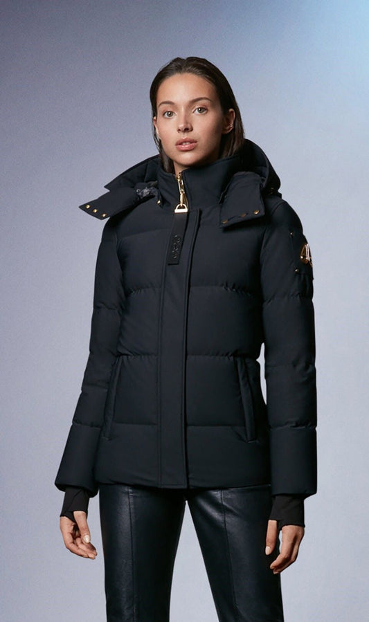 A person wearing a black, fitted puffer coat with a hood and metal detailing.