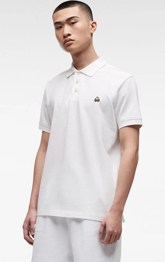 A man wearing a white polo shirt with a small cartoon eye on the chest.