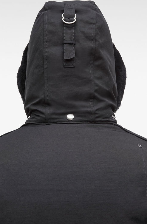 Close-up of the back of a black hooded jacket with faux fur trim.