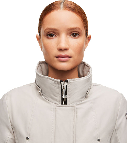 Close-up of a woman wearing a light grey puffer jacket with a high collar and zipper.