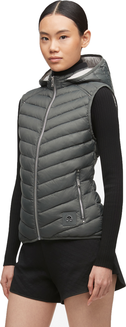 A woman wearing a gray quilted vest over a black long-sleeved shirt and black shorts.