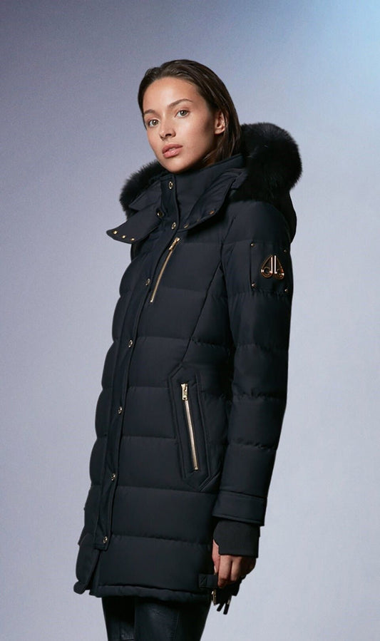 Woman wearing a black puffer coat with a fur-trimmed hood and gold zippers.