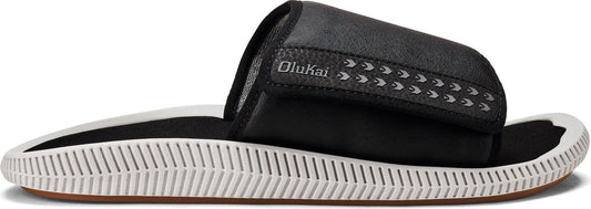 A slide sandal with a black strap and white sole. The strap has a decorative logo.