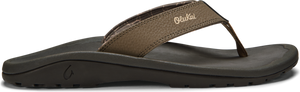 A brown sandal with the text "Olukai" on the upper.