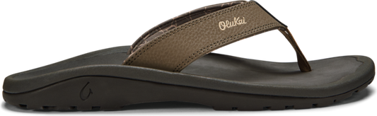 A brown sandal with the text "Olukai" on the upper.
