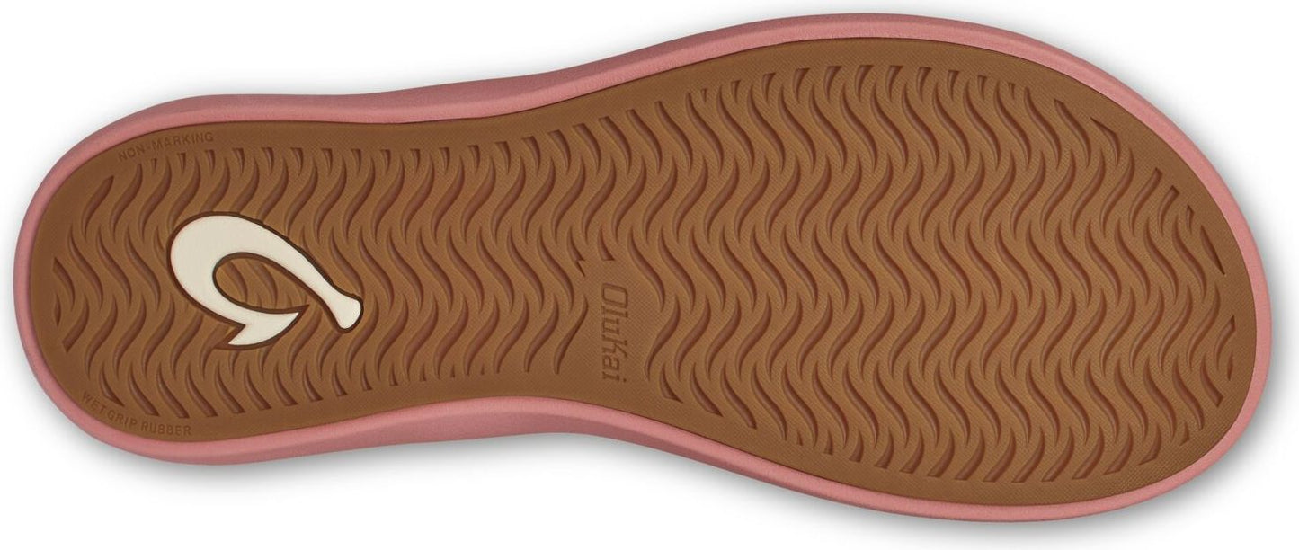 The sole of a sandal is brown with wavy tread and a pink trim, featuring a white hook logo on the side.