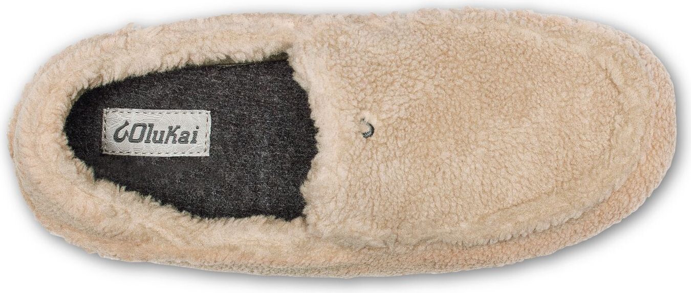a close-up shot of a cream-colored loafer slipper with the brand name 'OluKai' visible on the inner sole.