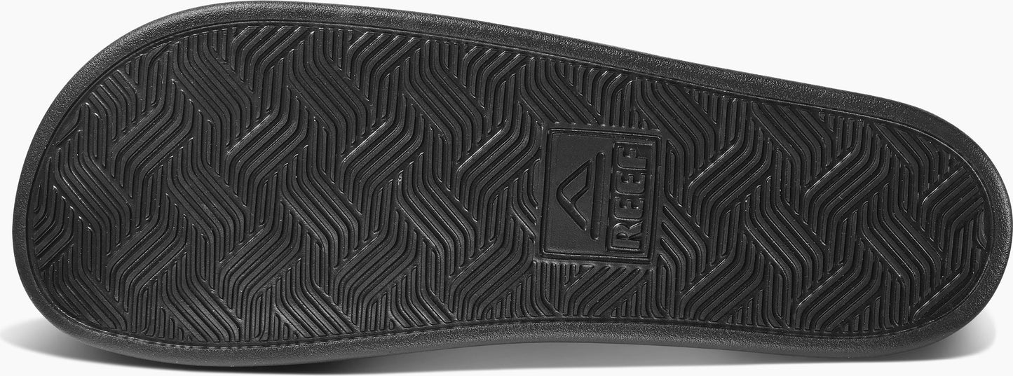 The sole of a black sandal with a wavy, geometric pattern and a rectangular logo.