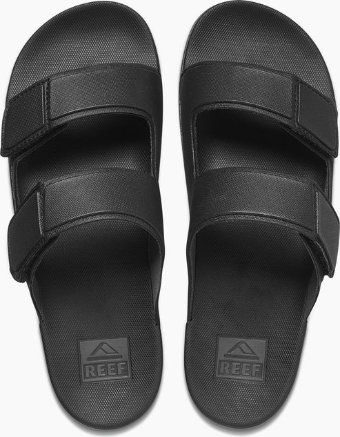 Two black Reef sandal slides with adjustable straps.