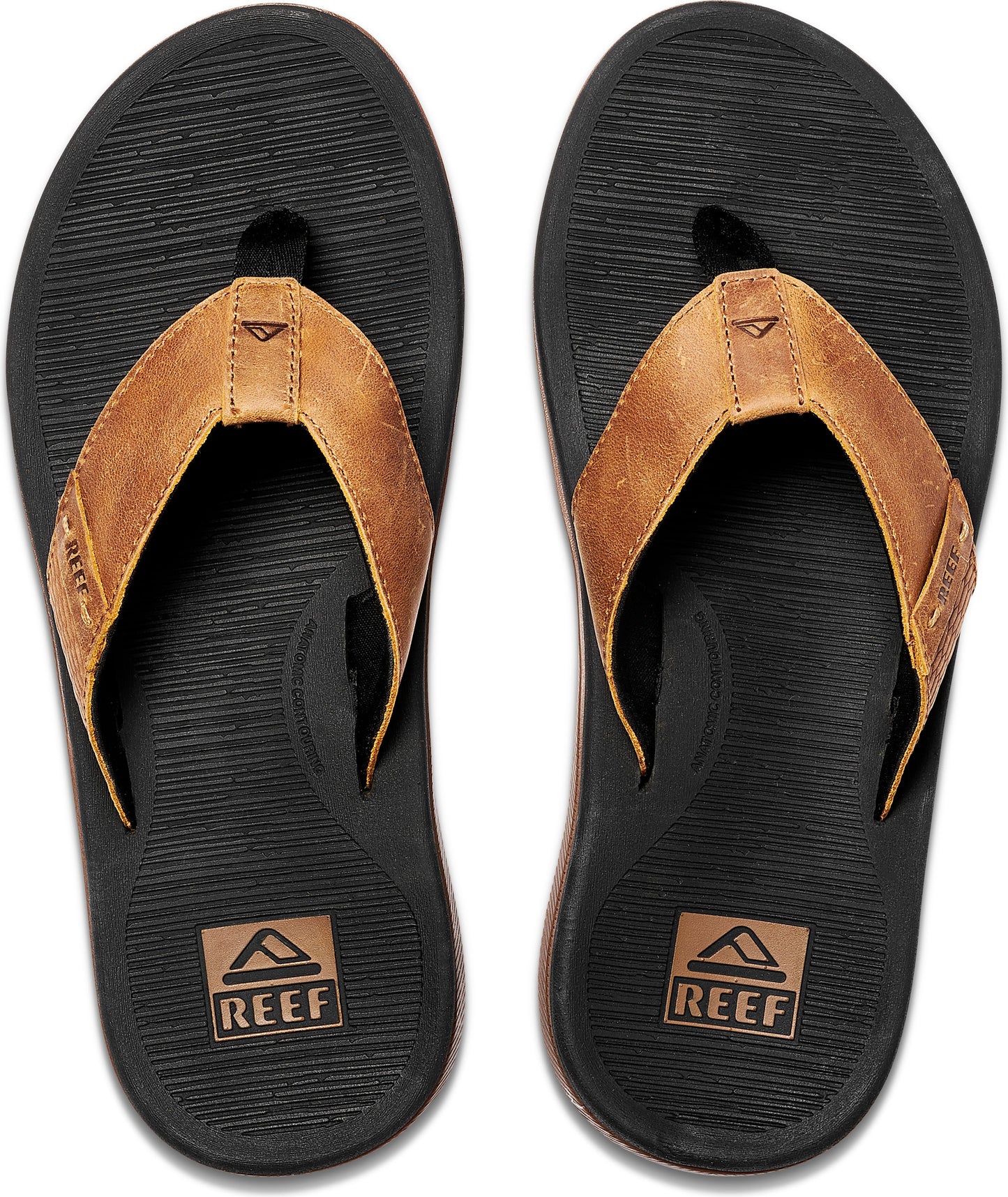 A pair of flip-flops showing a black sole with brown leather straps. The word REEF is displayed in a small box near the heel.