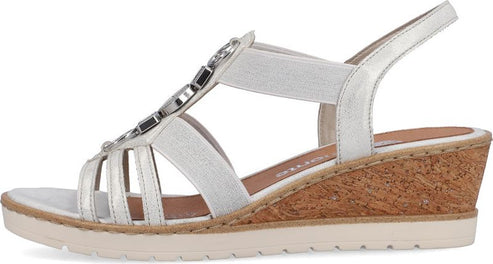 Side view of a white sandal with multiple straps, decorative jewels, cork wedge heel and white sole.