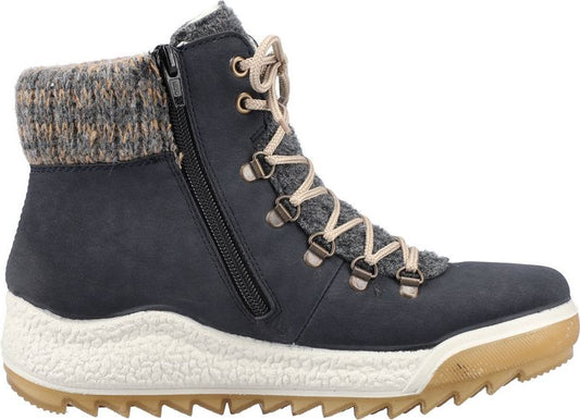 Side view of a dark blue ankle boot with beige laces, a side zipper, and a gray knit cuff, set on a thick, textured white and brown sole.