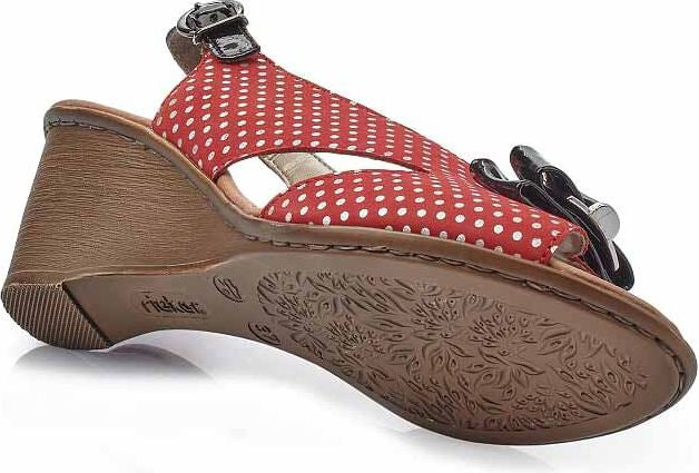 Low angle view of red and white polka dot sandal with black embellishment and a buckle strap.