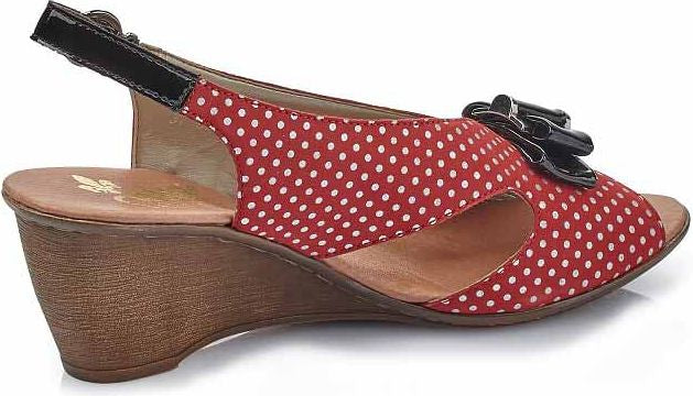 Red and white polka dot sandal with black straps and decorative flower on wedge heel.