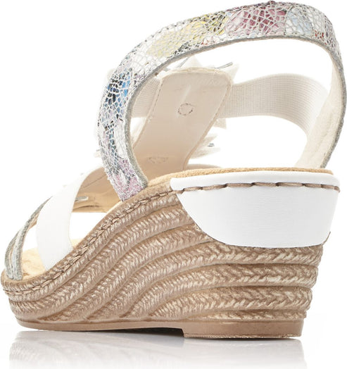 Wedge sandal with white straps, decorated with a flower, and an elastic ankle strap with a colorful pattern.