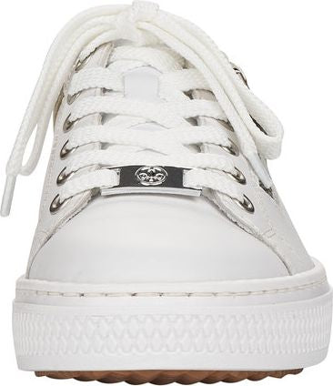 Frontal view of white sneakers with laces and decorative metal ornament.