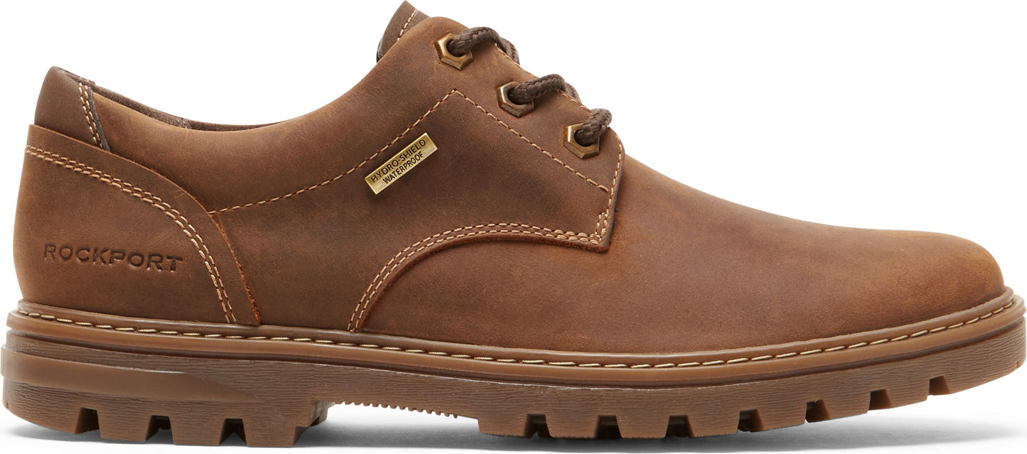 A brown leather shoe with a lug sole and the text "ROCKPORT" visible near the back.