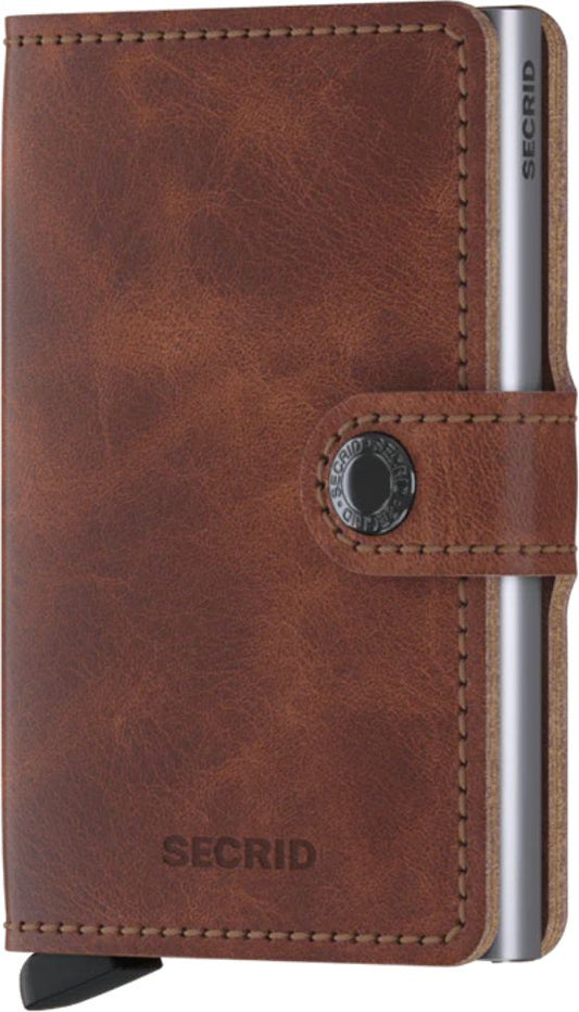 Brown leather cardholder with a button closure and a metal card slide.