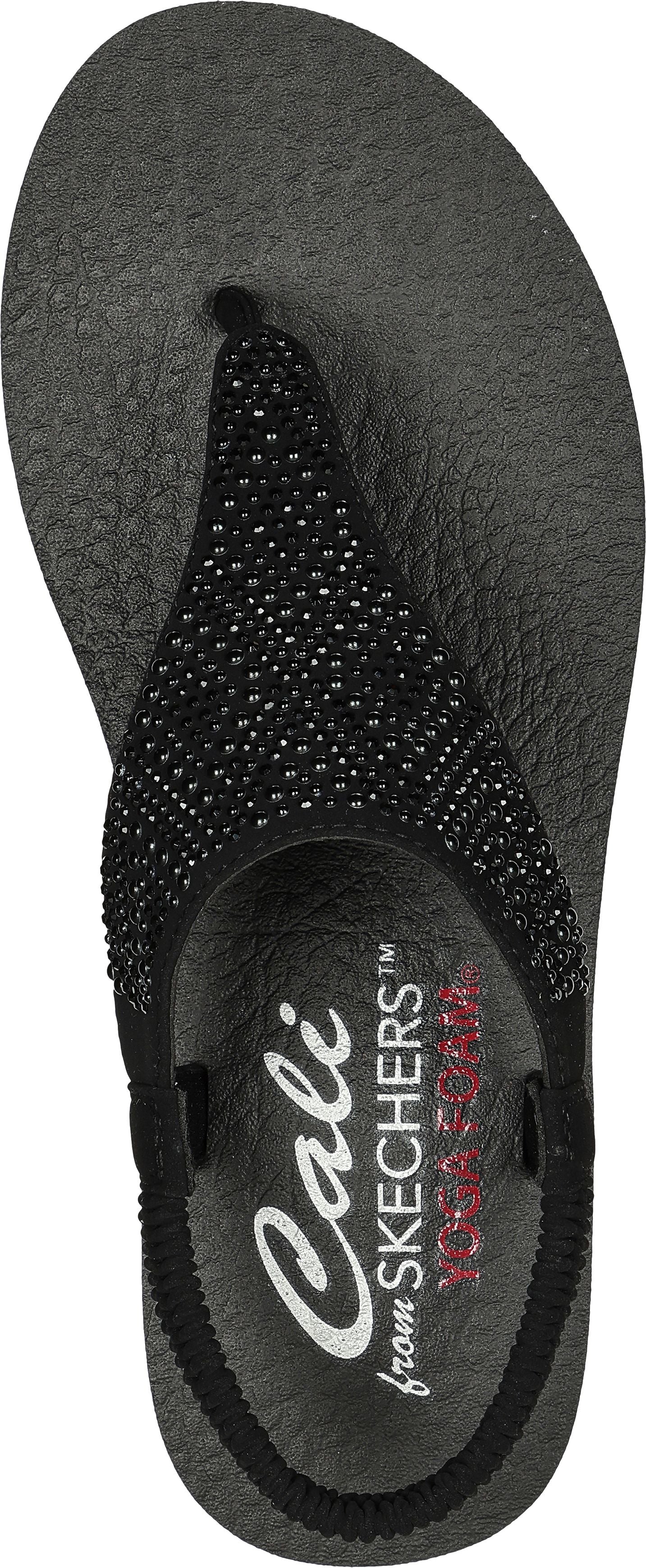 A close-up of a black sandal with a beaded strap.