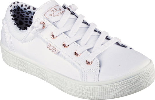 A white sneaker with a rounded toe, white laces, rose gold eyelets, a white sole, and a Dalmatian print lining.