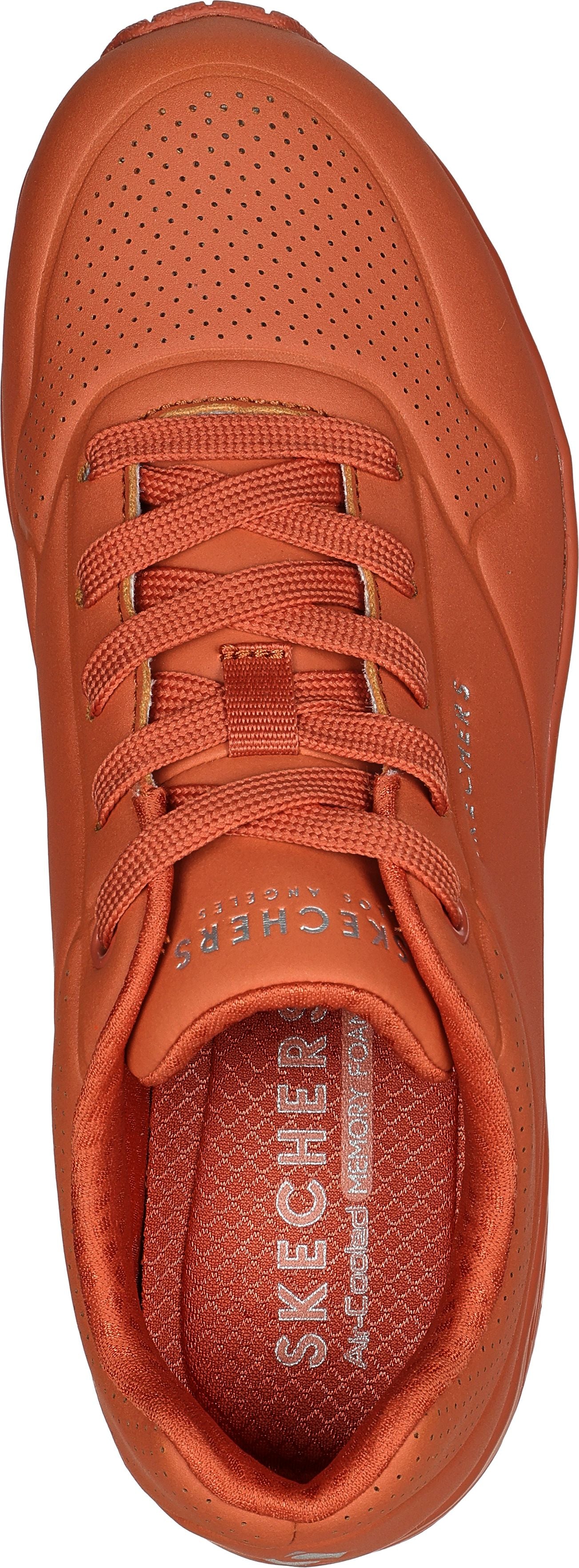 A close-up shot of an orange sneaker with a lace-up closure.
