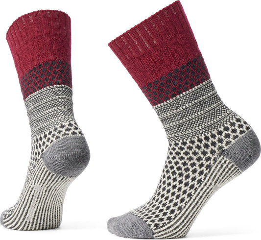 Two wool socks, one mostly visible and one partial, featuring a red top, a black and white geometric band, a white and gray design, and a gray heel and toe.