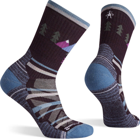 Two mid-calf length socks with a dark brown body and blue heels and toes featuring geometric patterns and stylized trees.
