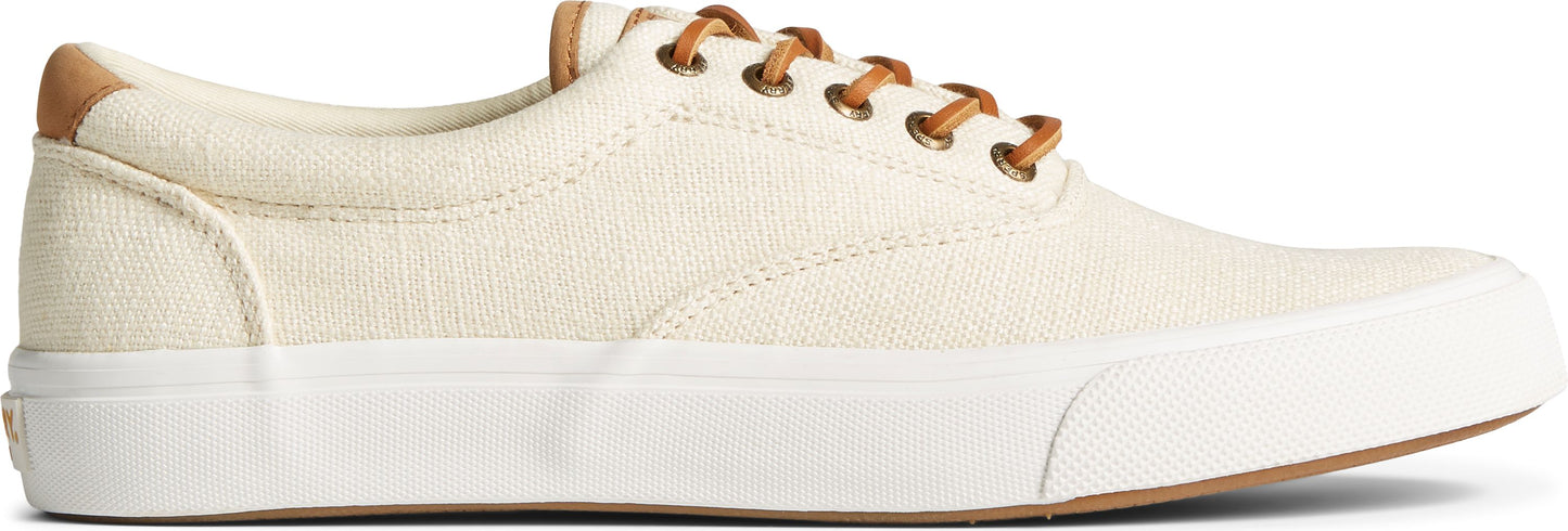 A canvas sneaker in an off-white color, featuring brown leather laces and heel accent, contrasted by a thick white rubber sole and a light brown outsole.