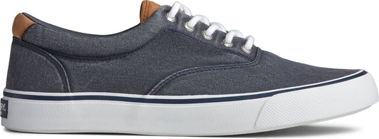 A navy blue canvas sneaker with white laces and a white sole. The heel has a tan leather patch.
